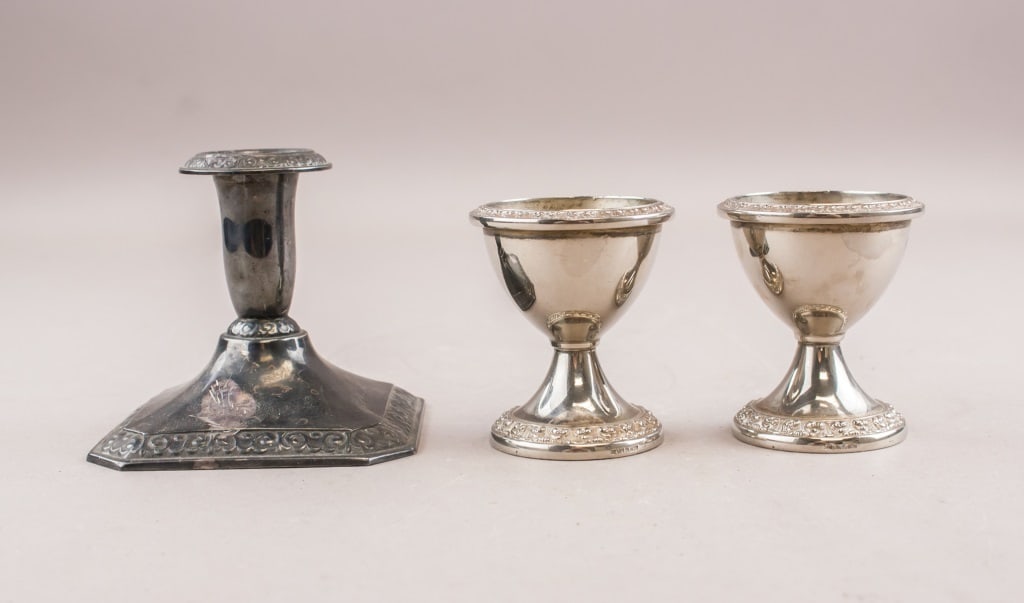 Silver-plated Candle Holder and 2 Egg Cups IANTHE: Silver-plated candle holder and 2 egg cups. Maker's mark "MADE IN IANTHE ENGLAND" inscribed on base. H: 8 cm, W: 8 cm, 211 g