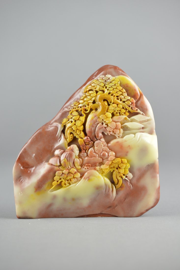 Chinese Carved Soapstone Boulder: Chinese carved soapstone boulder; featuring landscape scene with two figure underneath a lotus tree in relief; the stone of yellow, red and white tone; H: 14 cm, L: 13.5 cm, 746 grams