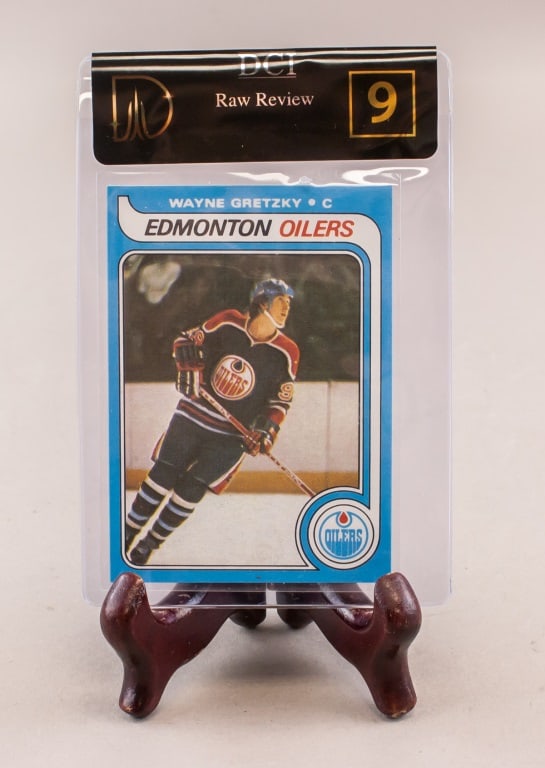 1979 O-Pee-Chee Wayne Gretzky Rookie DCI Raw 9: This iconic hockey card features Wayne Gretzky in his Edmonton Oilers uniform. Encased in a clear protective sleeve, the card is rated DCI Raw 9. On the back, detailed player statistics and informatio