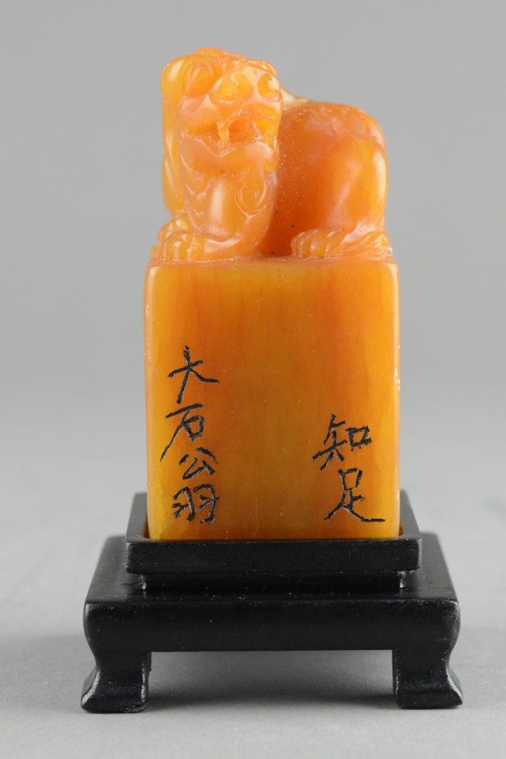 Shoushan Stone Carved Fu Dog Signed: Rectangular cross sectioned and surmounted with fu dog; the body inscribed with artist name Da Shi Yong; on wooden stand; H: 9 cm, L: 4 cm, W: 4 cm