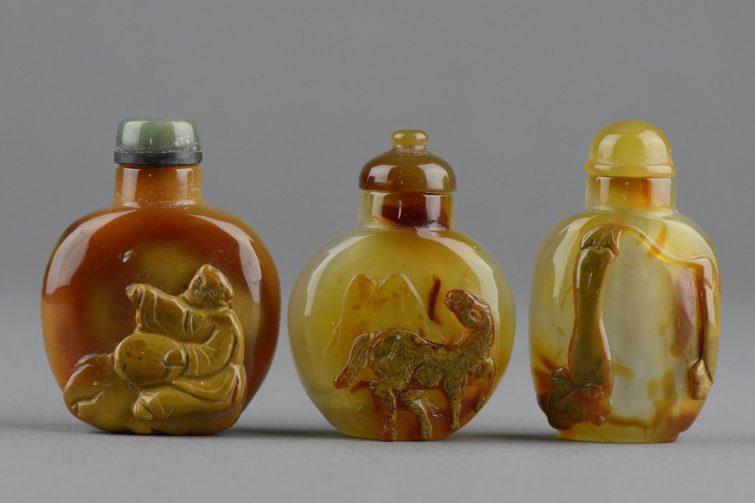 Three (3) Pieces Agate Snuff Bottles: Three pieces of agate snuff bottles with cap; featuring horse, female figure and gourd carvings; the stone of light caramel; (1/3) H: 5 cm, D: 3 cm, (2/3) H: 5 cm, D: 3cm. Provenance: T. Ng Collection