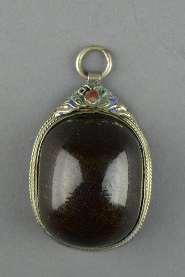 A Tibetan Rhinoceros Horn Pendant: Of oval shaped rhinoceros horn mounted onto silver frame decorated with floral and patterns. H: 5 cm, W: 4 cm, 66 grams.