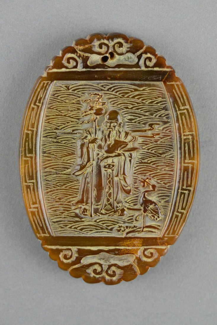 Chinese Rhinoceros Horn Carved Pendant 18th/19thC: Oval shape carved rhinoceros horn pendant, featuring Shao Lao and crane on one side, bats and cash coins on another side within stylized frame. H: 8 cm, W: 5.5 cm, 36 grams.