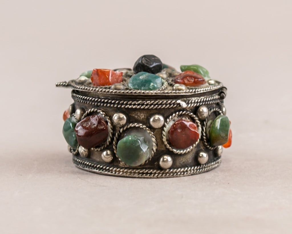 Vintage Silver-plated Gemstones Trinket Box: This box features intricate metalwork and is adorned with an array of multi-colored gemstones. The circular box is detailed with beaded edges and a lid encrusted with polished gemstones in hues of red