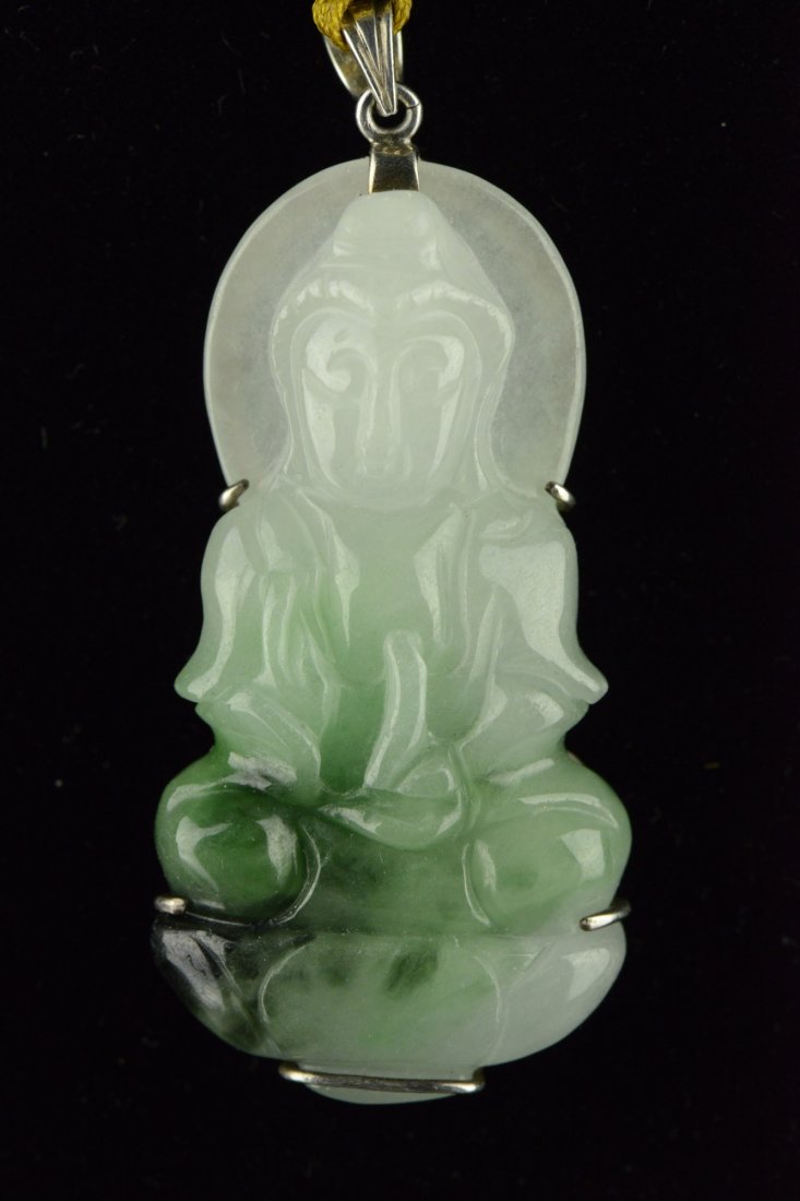 Finely Carved Green Jadeite Kwanyin Carved Pendant: Finely carved, of lustrous stone, featuring a Kwanyin on lotus plinth, The stone of white with green suffusions, on silver plated mounting. Suspending on yellow string. H: 5 cm, W: 2.5 cm, 25 grams.
