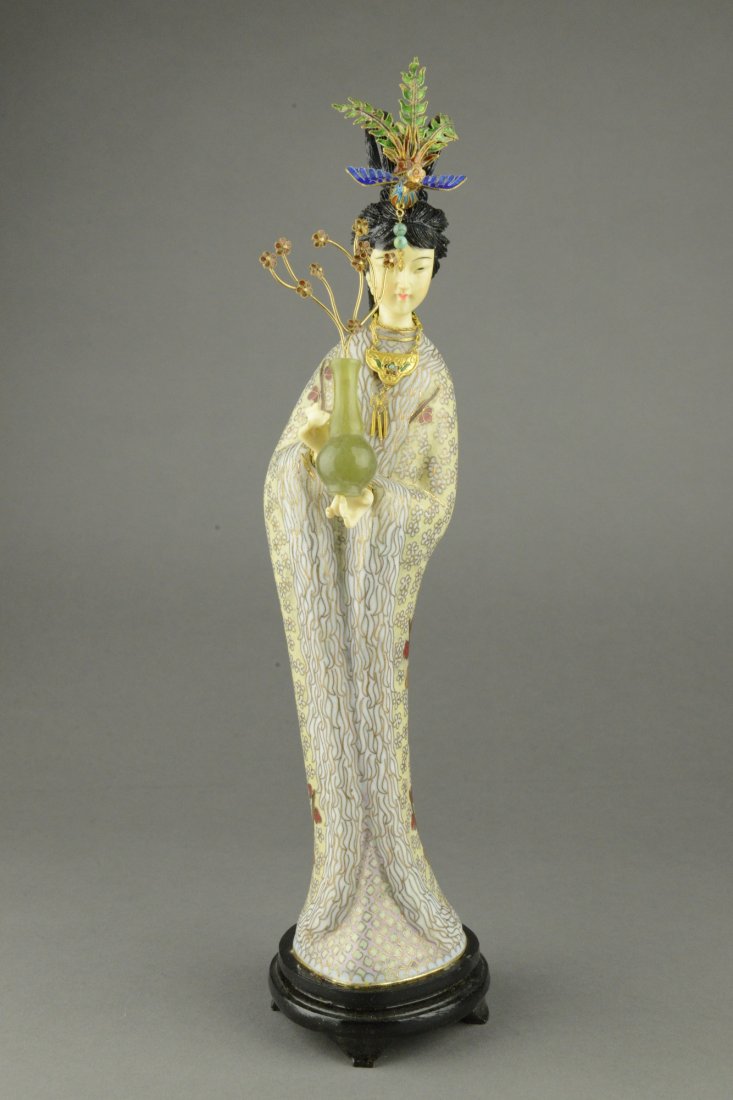Cloisonne Figure of Lady with Ivory Face and Hands: The lady figure is rendered in finely carved ivory with gilt flowing Cloisonne robe. Figure with detailed head ware and a delicate jade vase on hand. On wooden base. H: 37 cm, W: 6 cm.