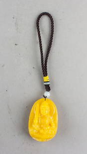 Chinese Yellow Amber Carved Buddha Pendant: Chinese yellow amber pendant finely carved in the round with a seated Buddha figure holding a sword in the right hand and a small object in the left, depicted with a serene facial expression and drape
