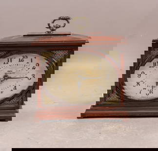 Vintage American Wood Electrical Mantle Clock: This vintage American wood electrical mantle clock features a rectangular wooden case with a rich, dark finish and a brass handle on top. The oval-shaped clock face displays black Arabic numerals and