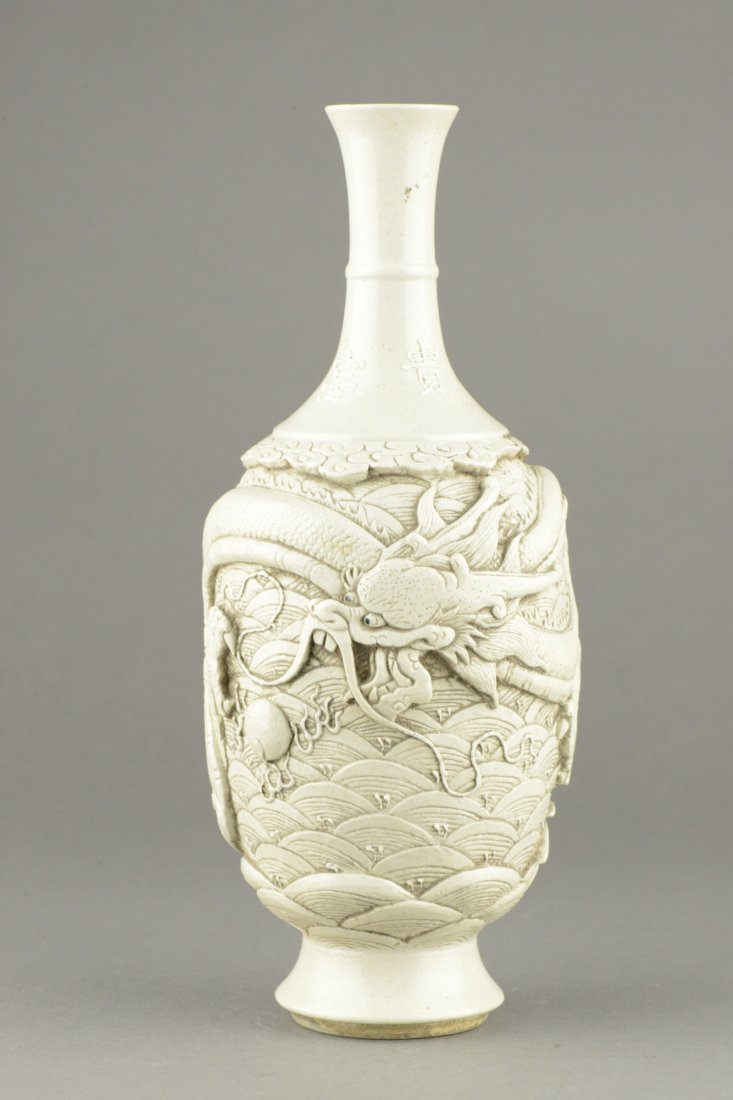 White Porcelain Carved Dragon Vase Signed: Chinese porcelain vase, of ovoid form, carved five-claw writhing dragon chasing flaming pearl on stylized sea waves, neck marked Chang Ming Fu Gui. Bottom marked Huang Bing Cha H: 25 cm, D: 9 cm, 757