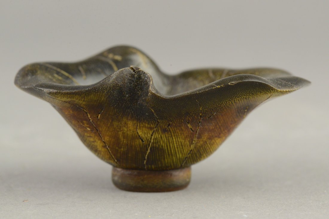Fine Rhinoceros Horn Lotus Leaf Form Libation Cup: Chinese rhinoceros horn carved cup, interior of the cup incised with veins rising to an irregular scalloped rim, the leaf motif repeated on the exterior rising from a short footing. H: 4 cm, W: 5 cm,