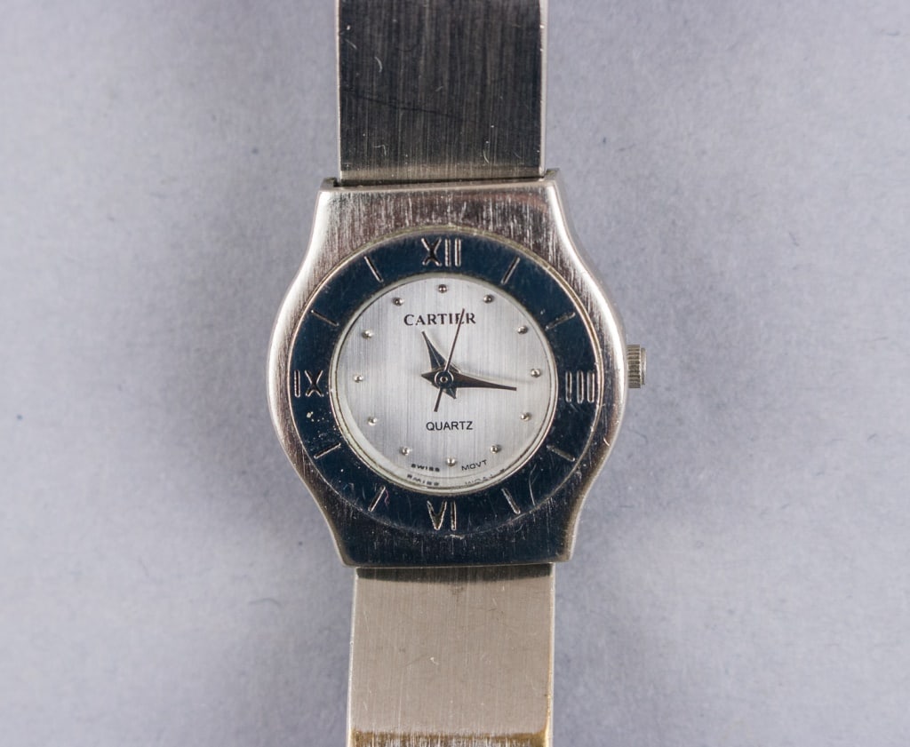 Vintage Cartier Quartz Stainless Steel Watch: Cartier quartz wristwatch in stainless steel, featuring a rectangular case with signature Roman numeral dial, blued steel hands, and sapphire cabochon crown. The watch is fitted with a stainless steel