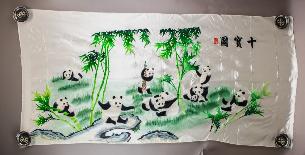 Chinese Embroidery on Silk Pandas: Chinese embroidery on silk depicting pandas in a bamboo forest, featuring eight pandas in various poses such as climbing, eating, and interacting. The embroidery is meticulously crafted with vibrant c