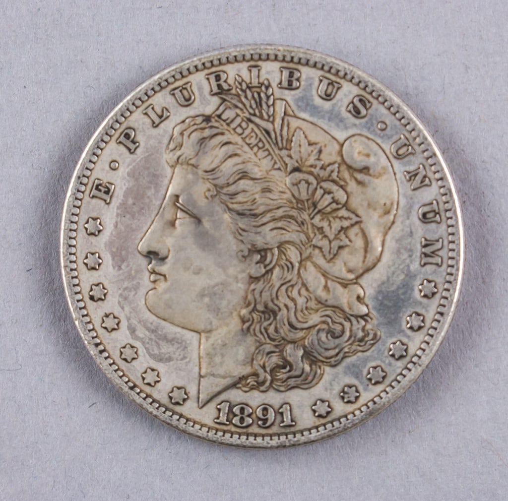 1891 American 1 Dollar Morgan Dollar Coin: A United States dollar dated 1891, bearing the Morgan design with Liberty head obverse and eagle reverse, showing standard legends including E PLURIBUS UNUM, UNITED STATES OF AMERICA, and ONE DOLLAR;