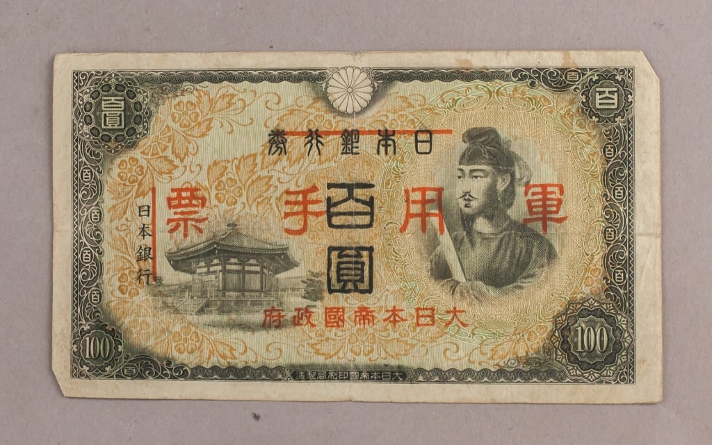 1945 Japan 100 Yen Military Banknote: A 100 Yen Japanese military banknote dated 1945, printed with denomination indicators, official government and military-use inscriptions, and architectural vignettes on both sides, showing multicolour