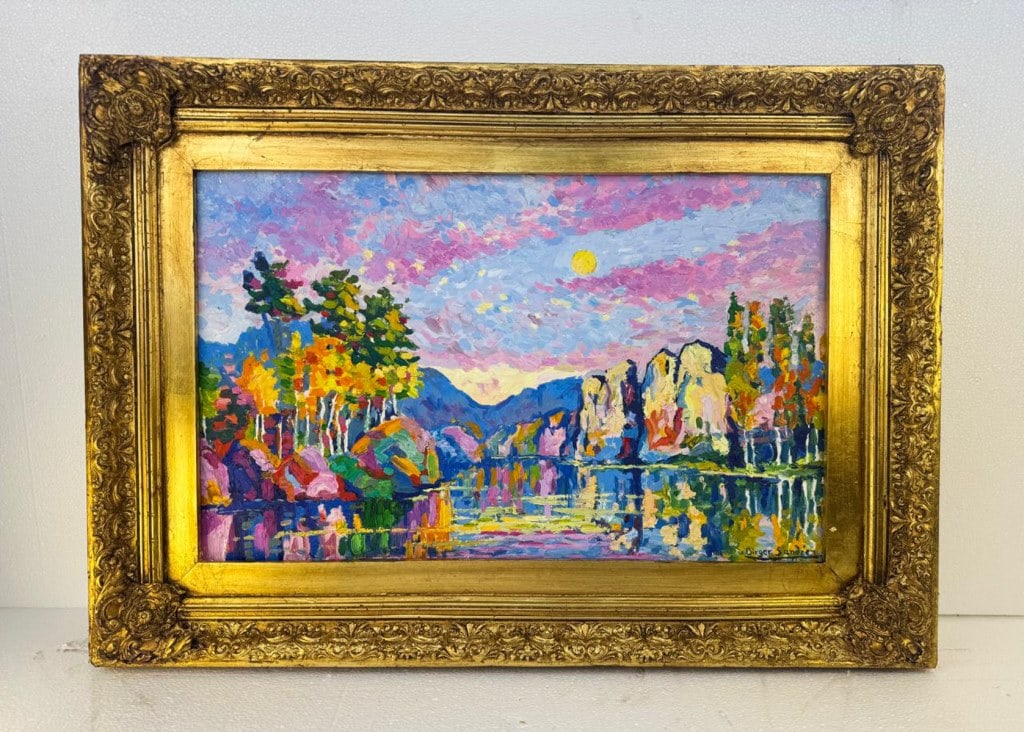 OOC Signed Birger Sandzen w/ American Art Label: Oil on canvas, framed. Attributed to Birger Sandzén (1871 - 1954). The painting depicts a lakeside landscape framed by rocky outcrops, clustered trees in autumnal tones, and a sky articulated in vivi