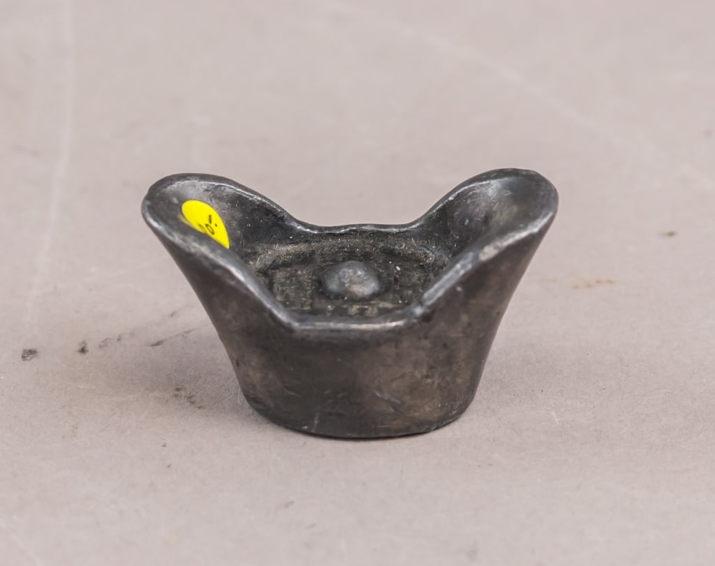 Chinese Dongchang Silver Sycee Boat Ingot: A small Chinese silver sycee of boat-shaped Dongchang Ingot, formed with curved ends and rounded upper surface, showing darkened patina throughout and a later applied inventory sticker on one rim. *Th