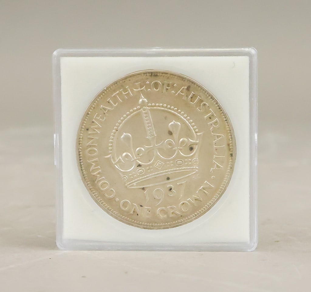 1937 Australian One Crown King George VI. Coin: A 1937 Australian one-crown coin issued for the coronation year of King George?VI, featuring St. Edward’s Crown at centre with the inscription “Commonwealth of Australia” above and “1937 O