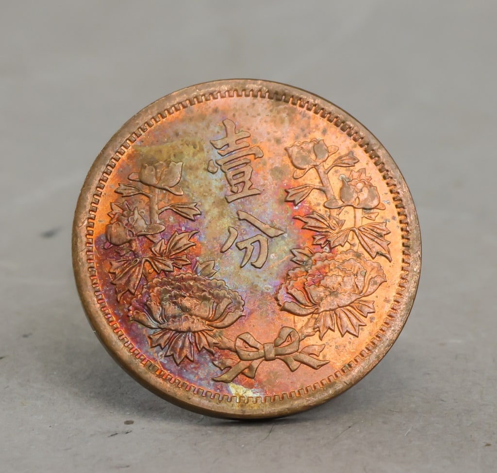 1939 Manchukuo 1 Fen Coin: 1939 Manchukuo 1 Fen coin, copper-colored issue bearing the central flag motif with four surrounding stars and “Great Manchukuo, Year 6” legends in Chinese characters. 7g.