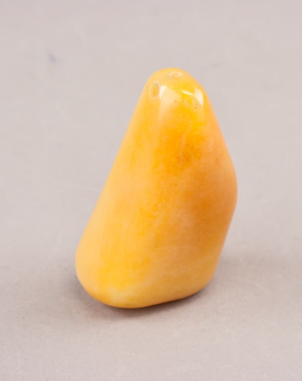 Chinese Tianhuang Stone Carved Pendant: A Chinese Tianhuang stone pendant of warm yellow-orange tone, polished to a smooth surface and shaped in an irregular upright form. The piece shows natural colour variation throughout. H: 7 cm, W: 4 c