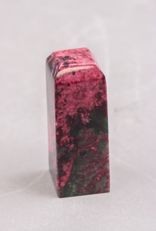 Chinese Natural Bloodstone Carved Seal: A Chinese natural bloodstone seal of rectangular form, polished on all sides and displaying mottled red and dark green coloration characteristic of the material. The top is bevelled and the stone show