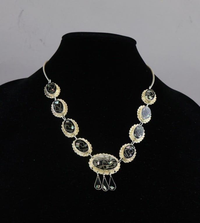 Vintage Alpaca Inlaid Abalone & Onyx Necklace: Vintage Mexico alpaca necklace composed of oval panels framed in scalloped metal borders, each inlaid with abalone and onyx arranged in geometric swirl motifs, the central pendant enlarged and suspend