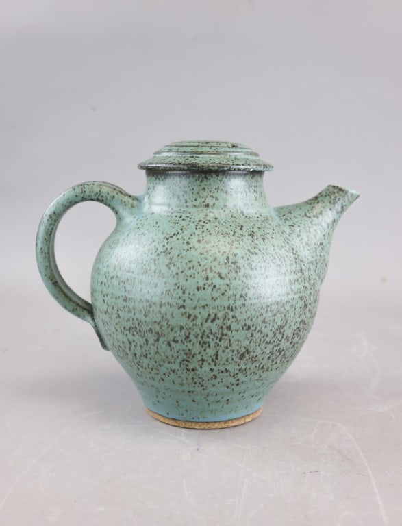 Japanese Meiji Pottery Green Teapot: Glazed-ceramic Japanese Meiji-period teapot with rounded body, short spout, curved handle, and fitted lid, finished in a mottled green surface with darker speckling and an unglazed foot revealing the 