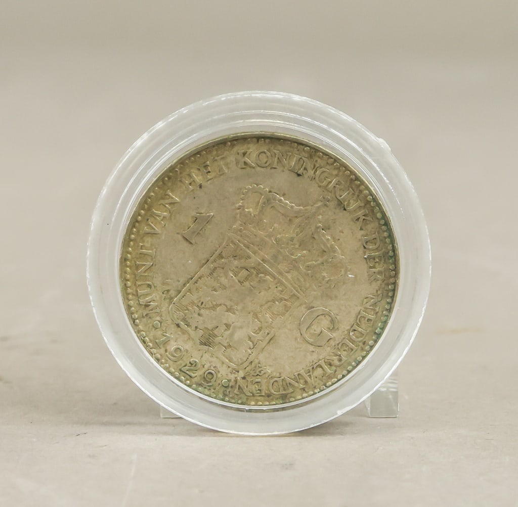 1929 Netherlands 1 Gulden Coin: 1929 Netherlands 1 Gulden silver coin bearing the crowned Dutch coat of arms flanked by the “1 – G” denomination and encircled by Munt van het Koninkrijk der Nederlanden legends, the piece