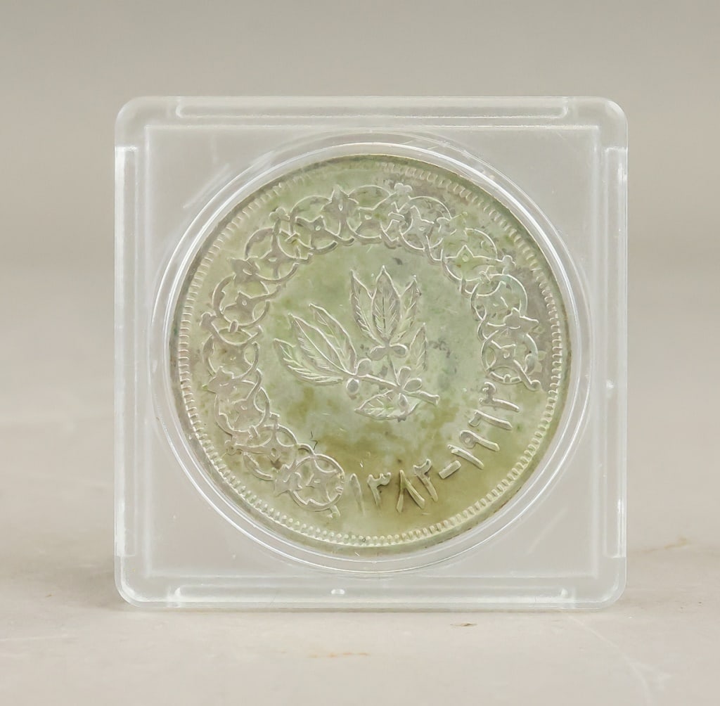 1963 North Yemen 1 Rial Coin: A 1963 North Yemen 1 rial coin, showing Arabic script and emblematic calligraphy on the obverse with date inscriptions on the reverse, framed by a wreath motif. H: 5 cm, W: 5 cm, 30g
