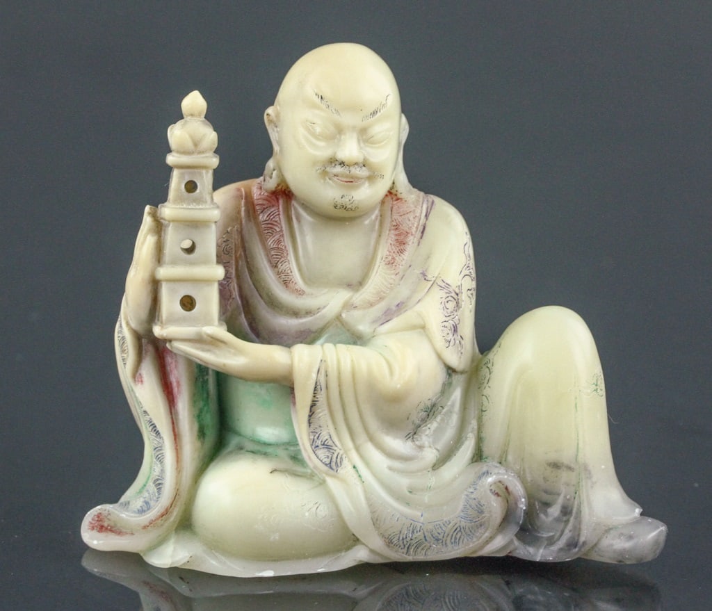 Fine 18th C Soapstone Carved Lohan Sculpture: This intricately carved soapstone sculpture depicts a Lohan seated in a serene posture. The figure is adorned with detailed robes featuring flowing patterns, and the facial expression reflects calm an