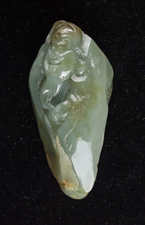 Chinese Green Jade Carved South Pole Boulder: Chinese green jade carved boulder, depicting a South Pole Immortal scene with a standing figure holding a ruyi scepter amid incised pine and rockwork. The jade is of rich green tone with variegated mo