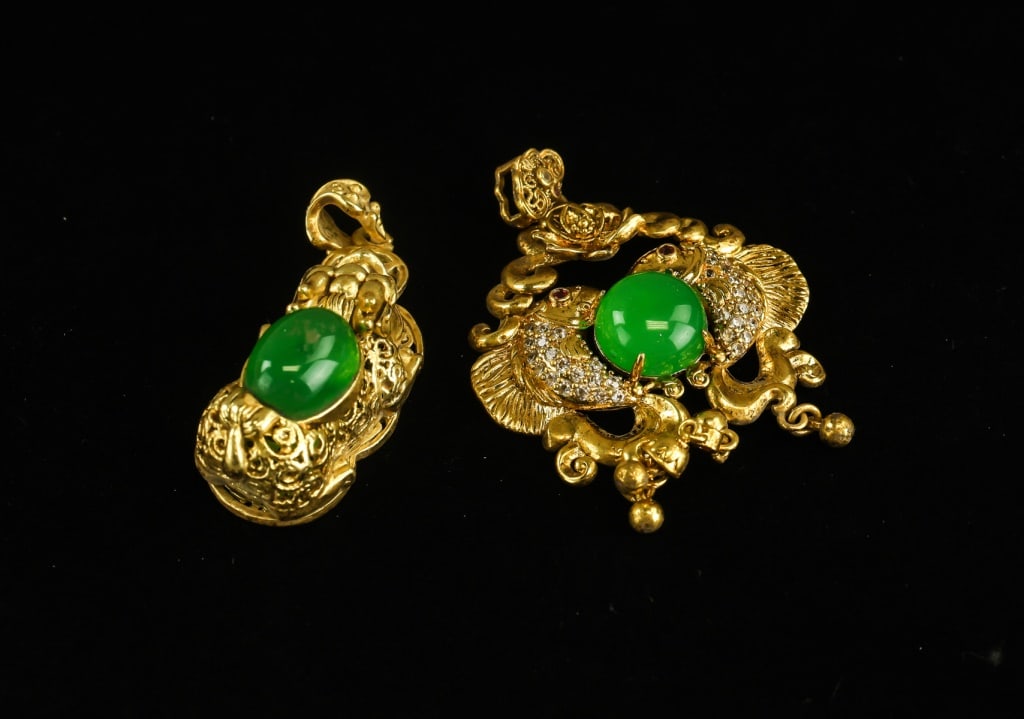 Chinese Gold-plated Green Stone Pendants 2pc: Chinese gold-plated green stone pendants, two pieces, each featuring an ornate openwork gold-tone mount centred with a polished green hardstone cabochon, one example further accented with small clear 