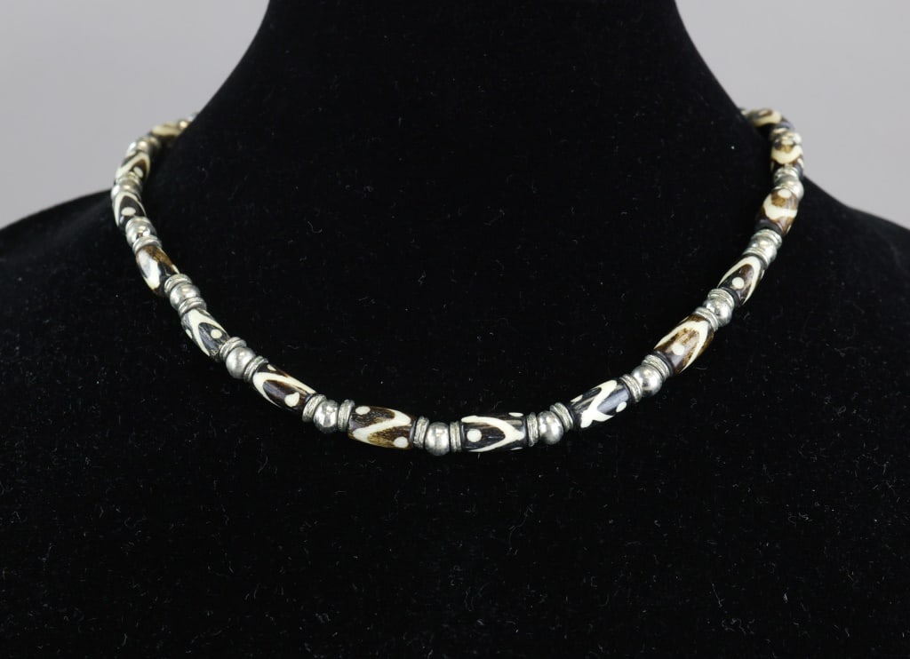 Vintage Chinese Dzi-style Beads Necklace: A vintage necklace composed of elongated Chinese Dzi-style beads displaying patterned brown, white, and black banding, arranged in alternating sequence with small silver-tone spacer beads. Dia: 16 cm,