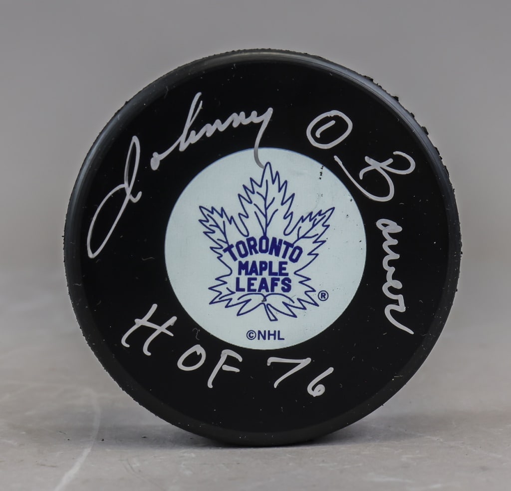 Vintage Maple Leafs Puck Signed Johnny Bower HOF76: Vintage Maple Leafs puck signed “Johnny Bower HOF76,” featuring the classic team logo at center with the signature and Hall of Fame inscription applied in silver marker. H: 3 cm, Dia: 8 cm, 19