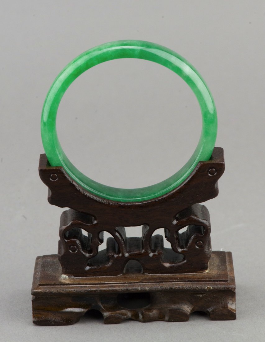 Chinese Emerald Green Jadeite Bangle: Chinese emerald green jadeite bangle, semi-rounded edge with fine polish. Wooden stand not included. D: 7 cm, inner D: 6 cm, 44 grams.
