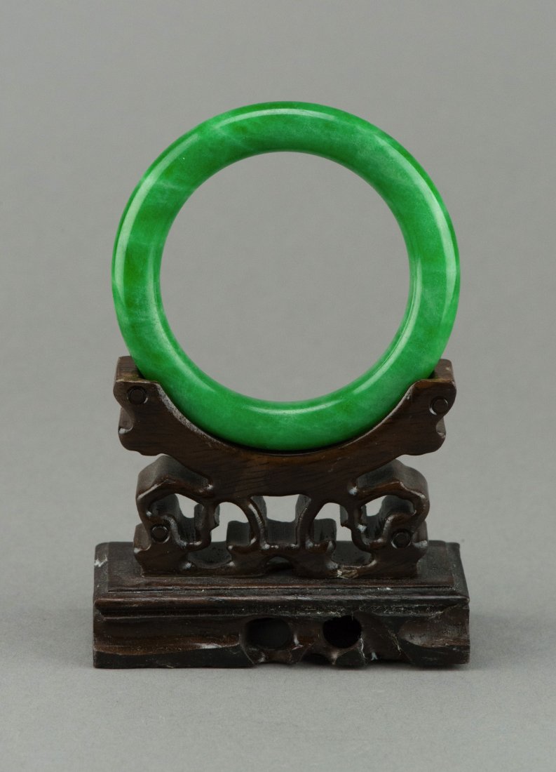Chinese Emerald Green Jadeite Bangle: Chinese jadeite carved circular bangle, of emerald green tone, rounded edge. Wood stand not included. D: 7 cm, inner D: 5.75 cm, 76 grams.
