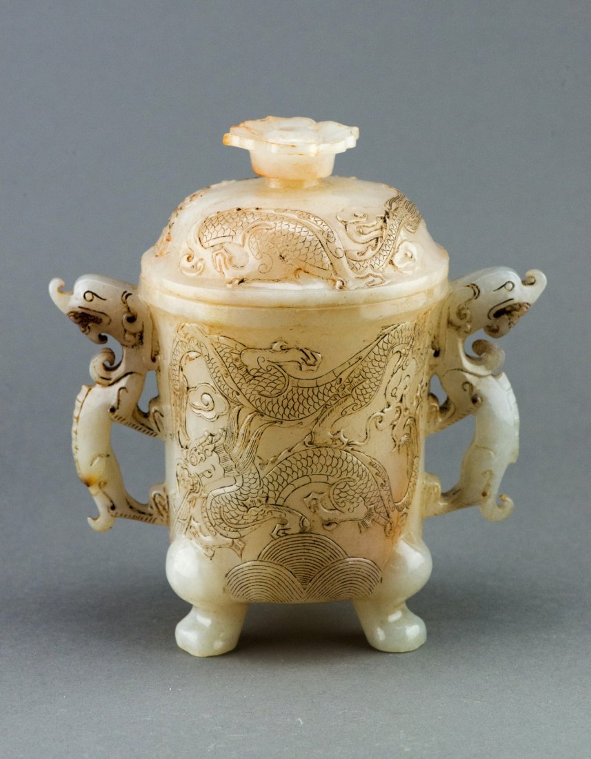 Chinese Han Style White Jade Dragon Vase: The cylindrical body supported on three ball foot, the body flanked with pair of dragon handles and decorated with dragon designs in low relief. H: 17 cm, W: 15 cm, D: 8 cm, 678 grams. Provenance: T. 