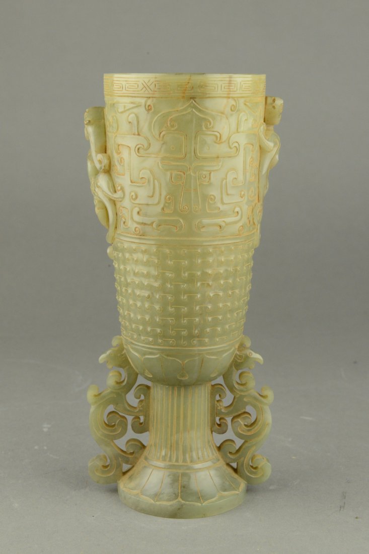 Chinese White Jade Carved Wine Vessel: Thinly potted, Chinese white jade carved wine cup, richly decorated with archaistic period designs, flanked with floral sprays and celadon tone. H: 23 cm, D: 8 cm, 693 grams. Provenance: T. Ng Collect
