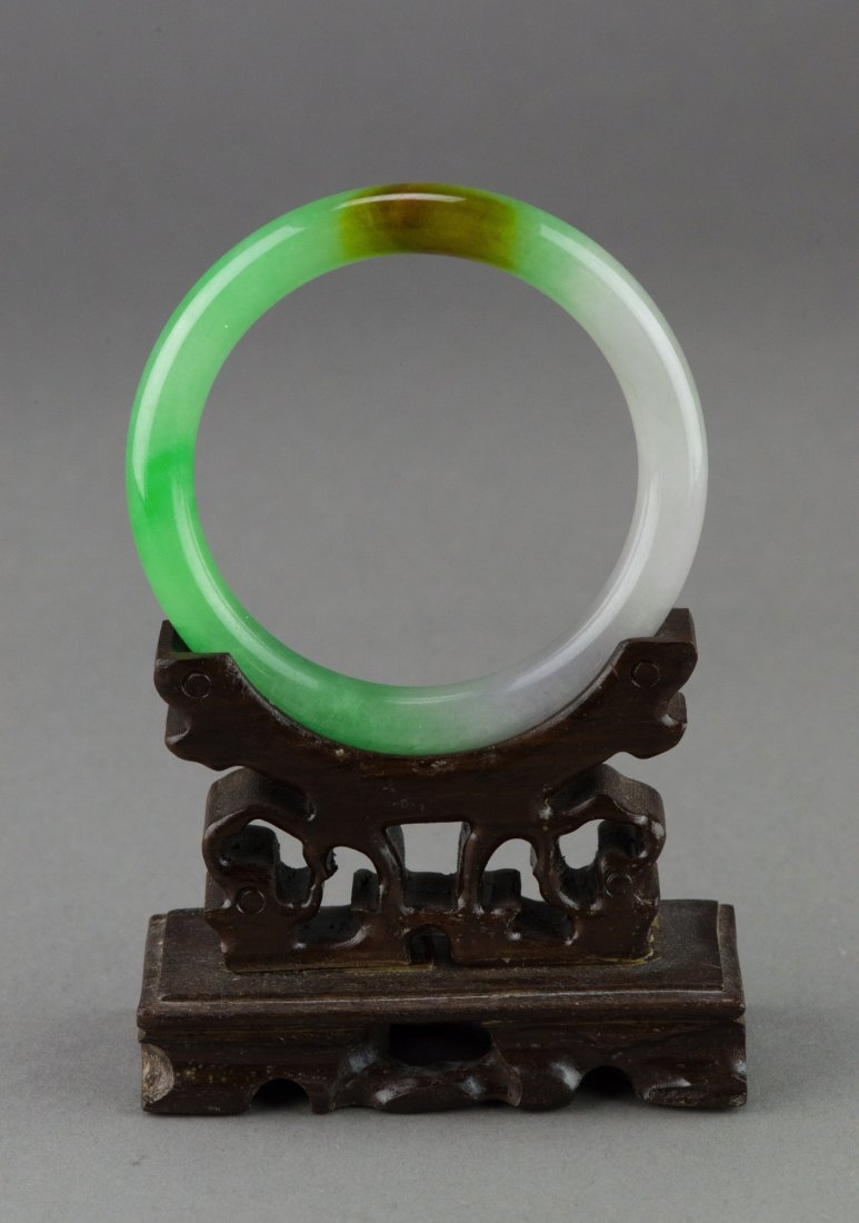 Fine Chinese Two Tone Emerald Green Jadeite Bangle: Fine Chinese jadeite bangle, of emerald green and white tone with brown suffusion, rounded edge with polished finish. Wooden stand not included. D: 8.5 cm, inner D: 6.3 cm, 66 grams.