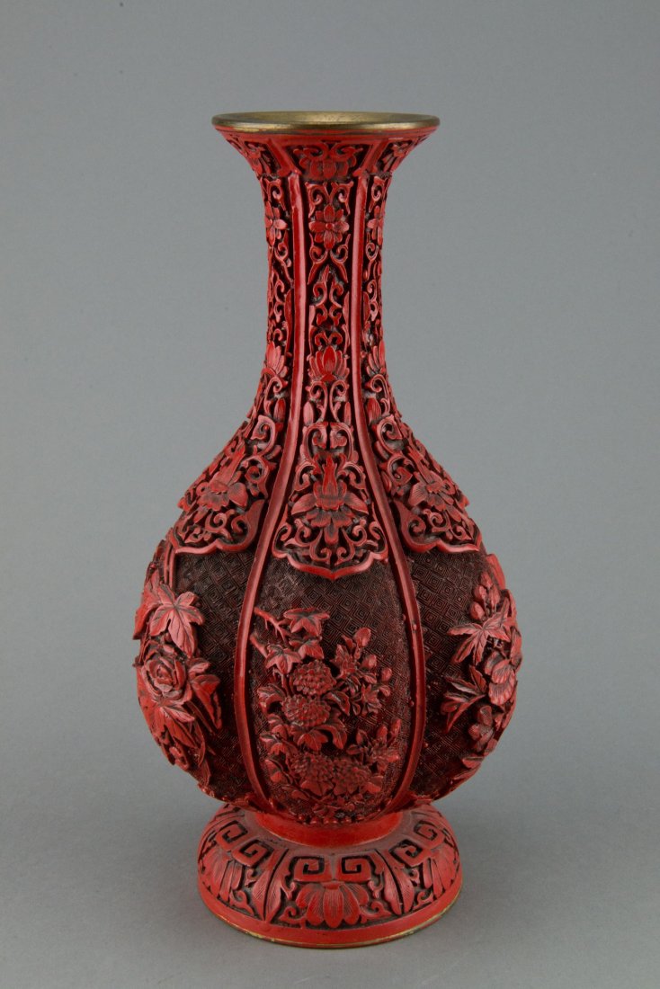 Chinese Red Lacquered Six Lobbed Flower Vase: The garlic shaped body covered with cinnabar red lacquer designs of lotus and peonies, resting on thick footing with bronze rims and foot. H: 32 cm, W: 16 cm, 1635 grams.
