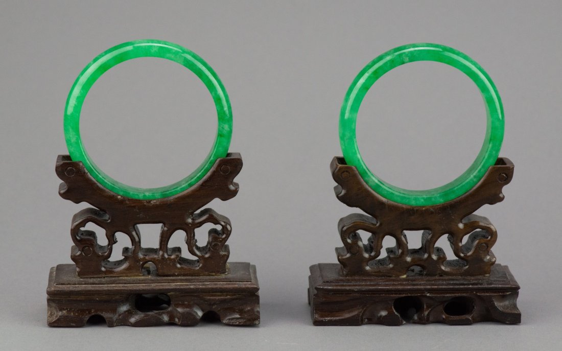Pair of Chinese Emerald Green Jadeite Bangles: Pair of Chinese jadeite carved circular bangles, semi-rounded edge. Wooden stands not included. D: 7 cm, inner D: 6 cm, total 91 grams.