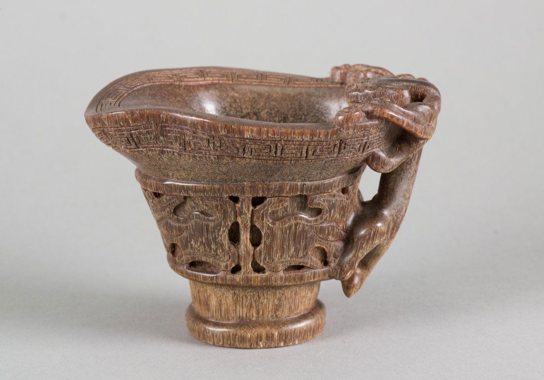 Chinese Horn Carved Cup Signed: Chinese horn carved libation cup; featuring openwork carving on sides with meandering key-fret border on rim; clambering chilong handles; and supported on short foot rim; four-character mark on base;
