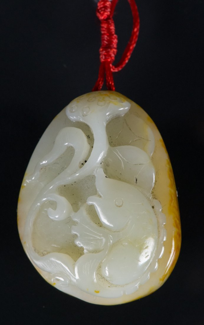 Chinese White Jade Carved Fish with Lotus: 巧色雕玉及莲花玉挂件 Chinese jade carved pebble boulder pendat; featuring fish in relief; of translucent white tone with mutton fat suffusio