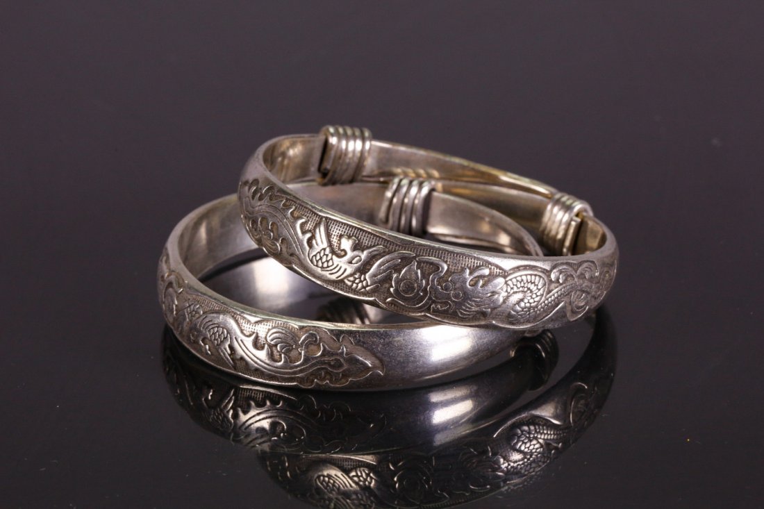 Pair of Chinese Silver Bracelets: Pair of Chinese silver bracelets; featuring carvings of dragon and phoenix; with Zu Yin (Pure Silver) mark inside of the bracelets; D: 7 cm, 90 grams total
