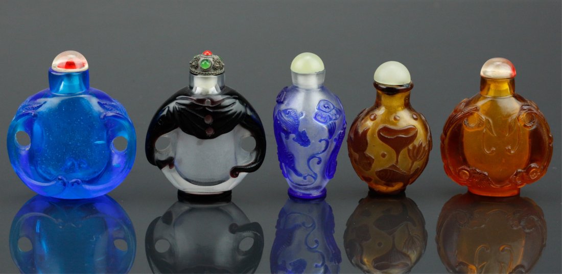 Five (5) Chinese Peking Glass Snuff Bottles: Five pieces of Chinese Peking glass snuff bottles; featuring low-relief carvings of animals and lotus on body; of brown, blue and black tone; H: 6.5 cm, W: 6 cm, 298 grams