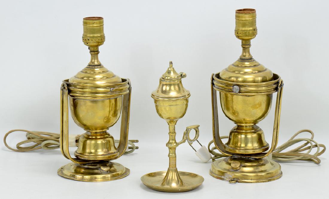 Three Antique Brass Lamps: A pair of electrified gimbal lamp wall sconces, Each 11" tall, 5" wide. A turned and cast brass whale oil finger lamp. 8" tall.