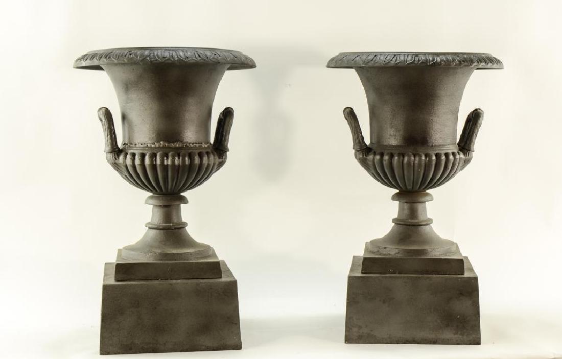 Pair of Cast Iron Garden Urns: Each restored and refinished. One with a full weld around the middle. Each setup as Interior End Tables with Custom Cut Glass Tops. Signed J.W. Fiske N.Y. Each measures 25" tall x 16" wide. Keywords: