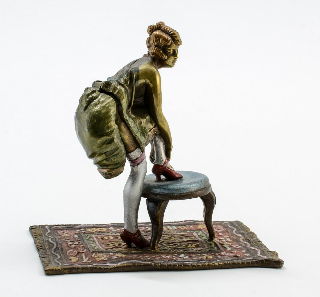 Naughty Vienna Bronze: Cold Painted Austrian Bronze Figure of a woman adjusting her shoe while stepping on a stool. Cast Directly to an Oriental rug. The back of her skirt lifts up to show an anatomically Correct bottom. Fa