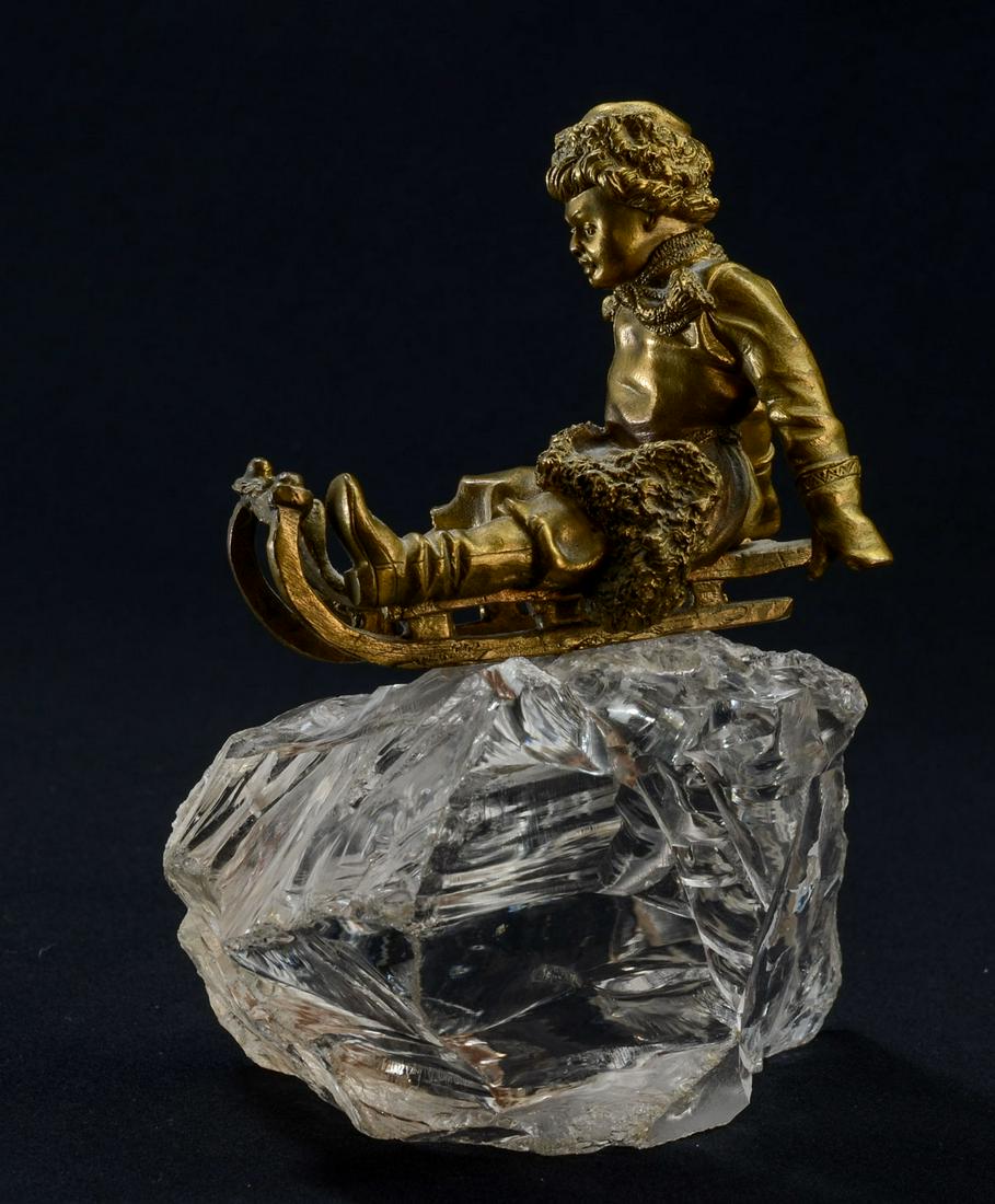 Russian Bronze & Rock Crystal Group: Gilt Bronze Figure of a child riding a Sled, set atop a piece of Rock Crystal. Each Piece is loose, some chipping to the top of the crystal. Bronze is unsigned. 6" x 3.5" x 4.5". Keywords: Russia, Art