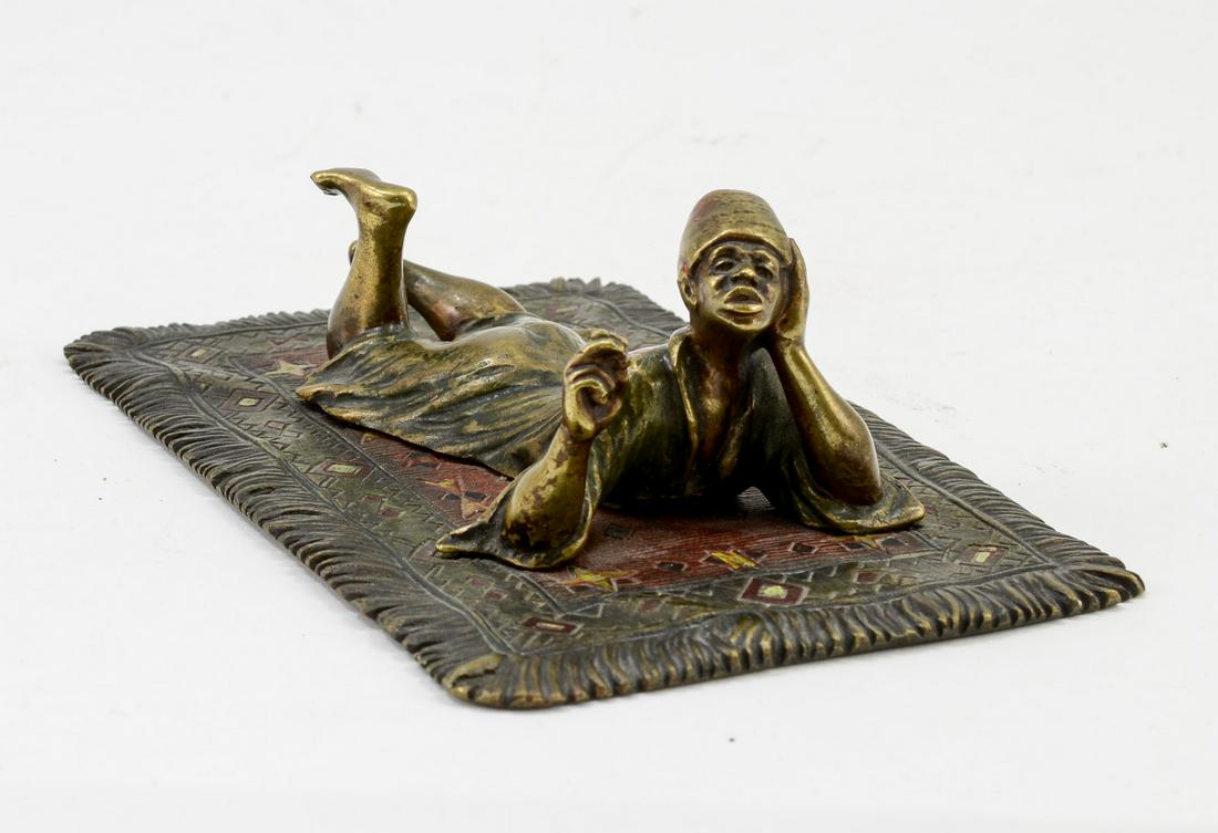 Orientalist Vienna Bronze Figure: Signed with "B" in Vase for Franz Bergman along with AUSTRIA and GESCHULTZ. Depicts a young man lying on an oriental rug smoking. Cold Painted, paint wear. Figure is riveted to carpet. Keywords: Austr
