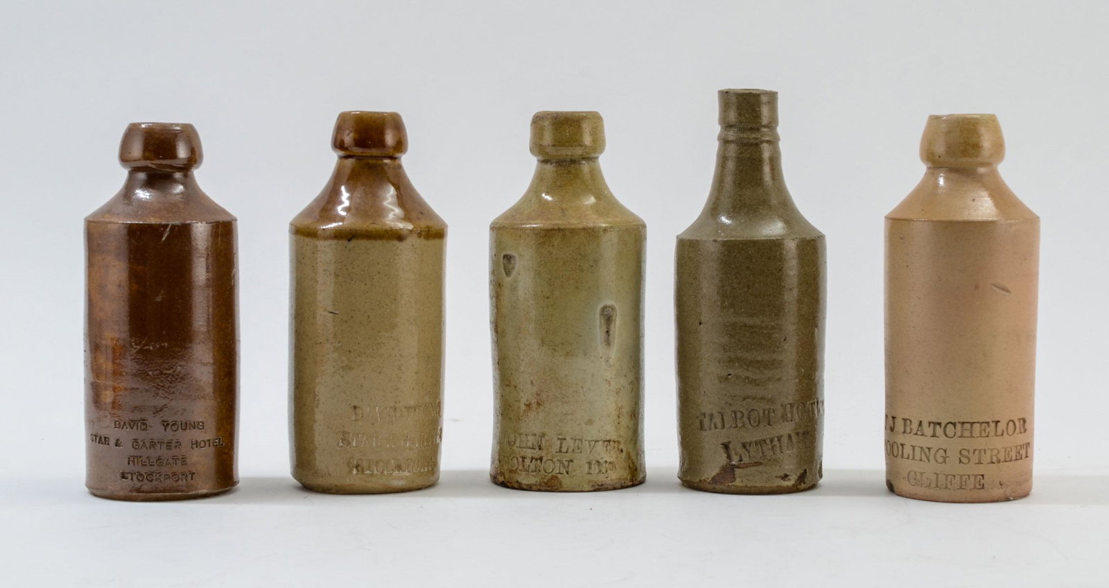 Five Stoneware Bottles: This group of stoneware bottles typically used for ginger beer, Mead, etc. There is a 7 ' bottle marked Talbot Hotel Lytham, 7" marked David Young Star & Carter Stockport, 6 1/2" Bottle marked J J Bat